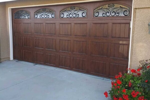 Alt Text Walnut finish short-panel garage door featuring arched windows with decorative wrought iron inserts.