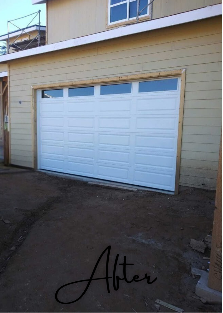 Newly installed white garage door with windows on a home under construction