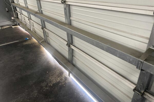 Interior view of a white sectional garage door showing horizontal steel reinforcement struts and hinges.