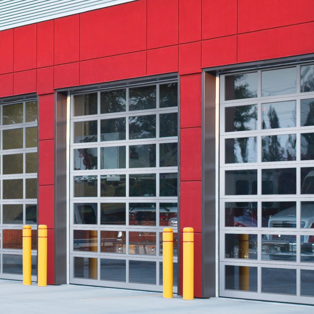 Modern commercial building with glass sectional garage doors and red exterior panels in Redlands, CA.