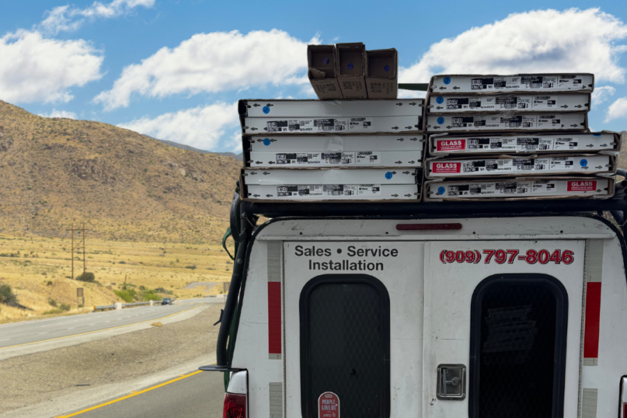 A Lloyd Copelan Garage Doors service truck loaded with Clopay door boxes driving on a highway toward an installation. Text overlay reads: Another Day, Another Door. Is yours next?
