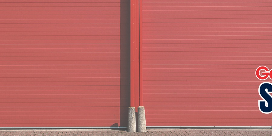 Red commercial roll-up steel door header banner with text reading Garage Door Services Since 1972.