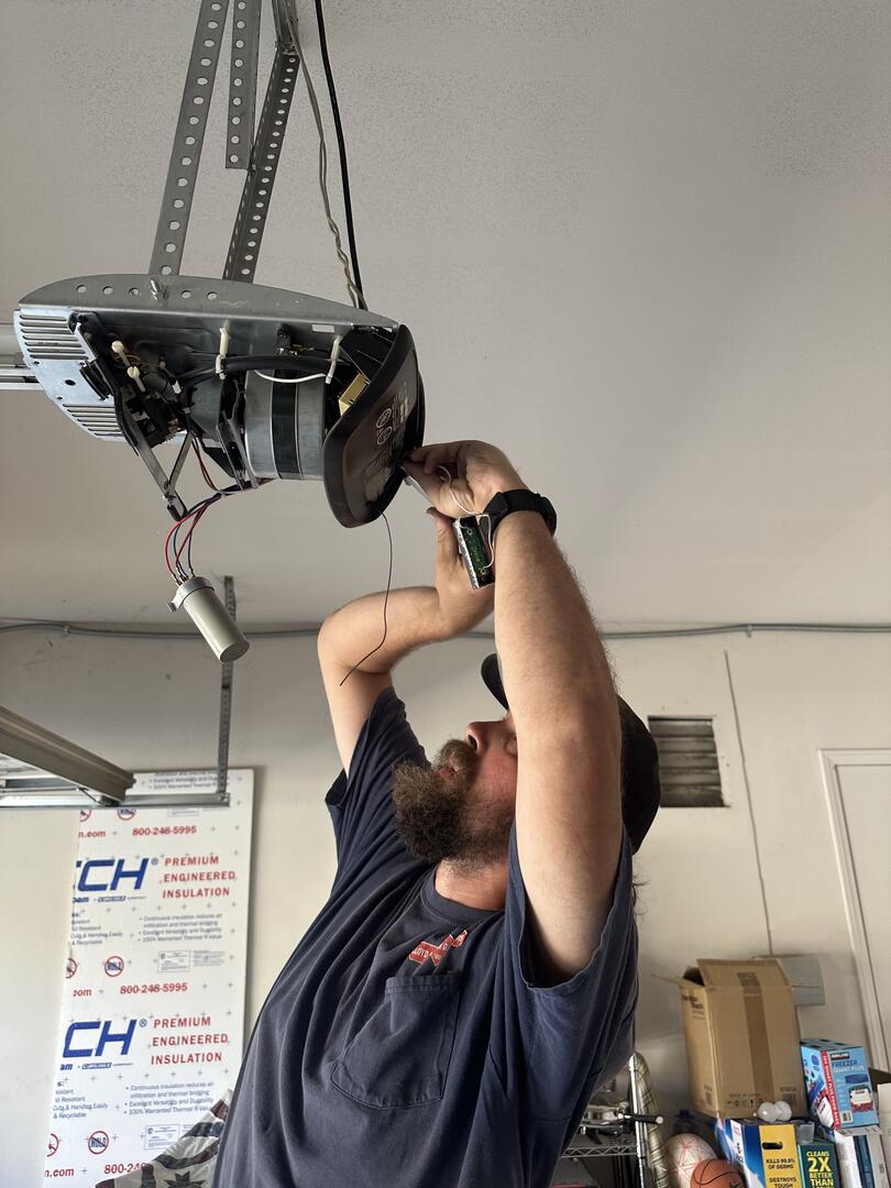 Lloyd Copelan technician inspecting the internal components of a ceiling-mounted garage door opener
