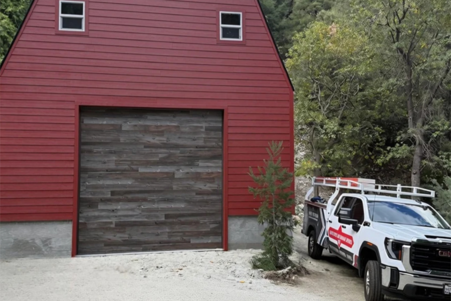 12×12 Clopay Modern Steel Ultra-Grain Plank garage door in Barnwood on a classic red barn