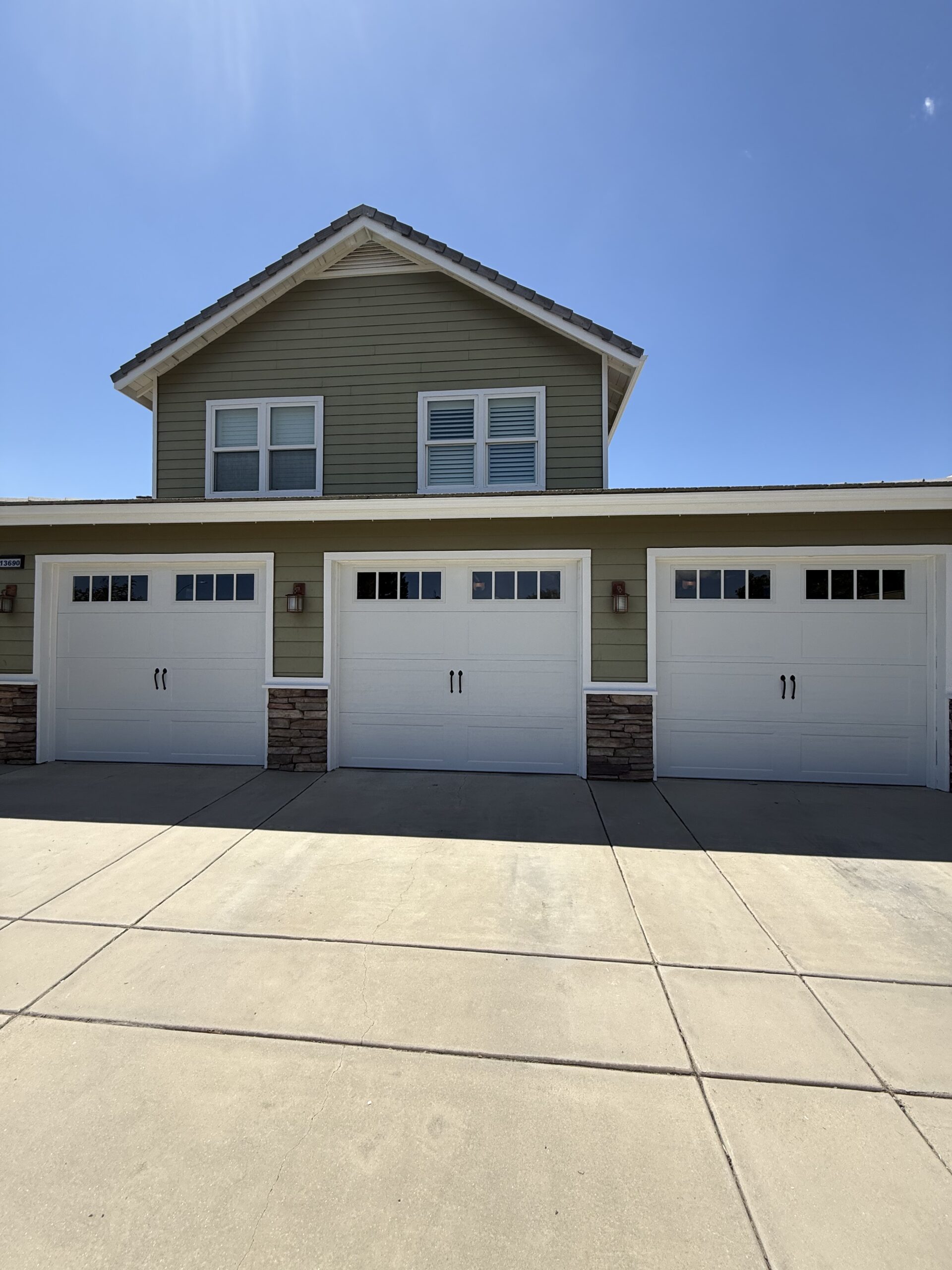 Three Bridgeport garage doors with Shaker-style inset panels and decorative hardware in Yucaipa.